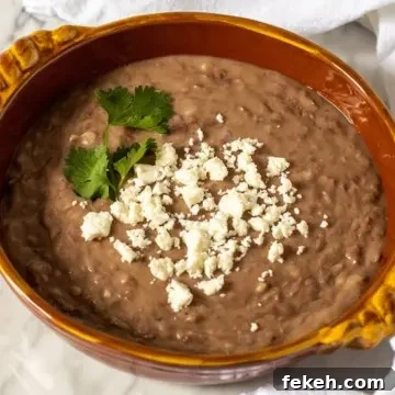 Homestyle Refried Beans Recipe for Creamy, Flavorful Sides 9 Refried beans in serving dish with queso fresco.