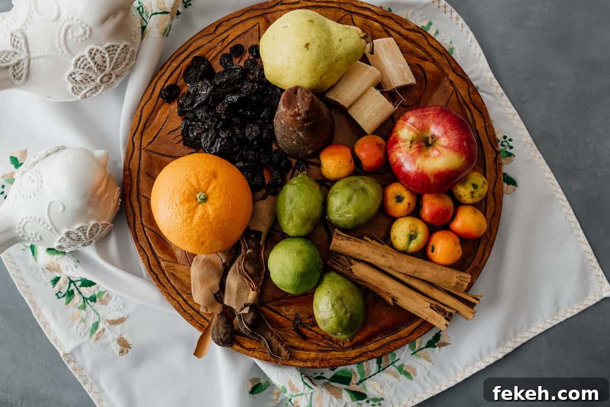Canela: The Story and Uses of Mexican Cinnamon 5 round wooden platter with apple, orange, pear, sugarcane, canela sticks, tamarind, guavas, a pyramid of piloncillo, and dried cherries atop an embroidered white napkin with green and pale pink vining flowers.