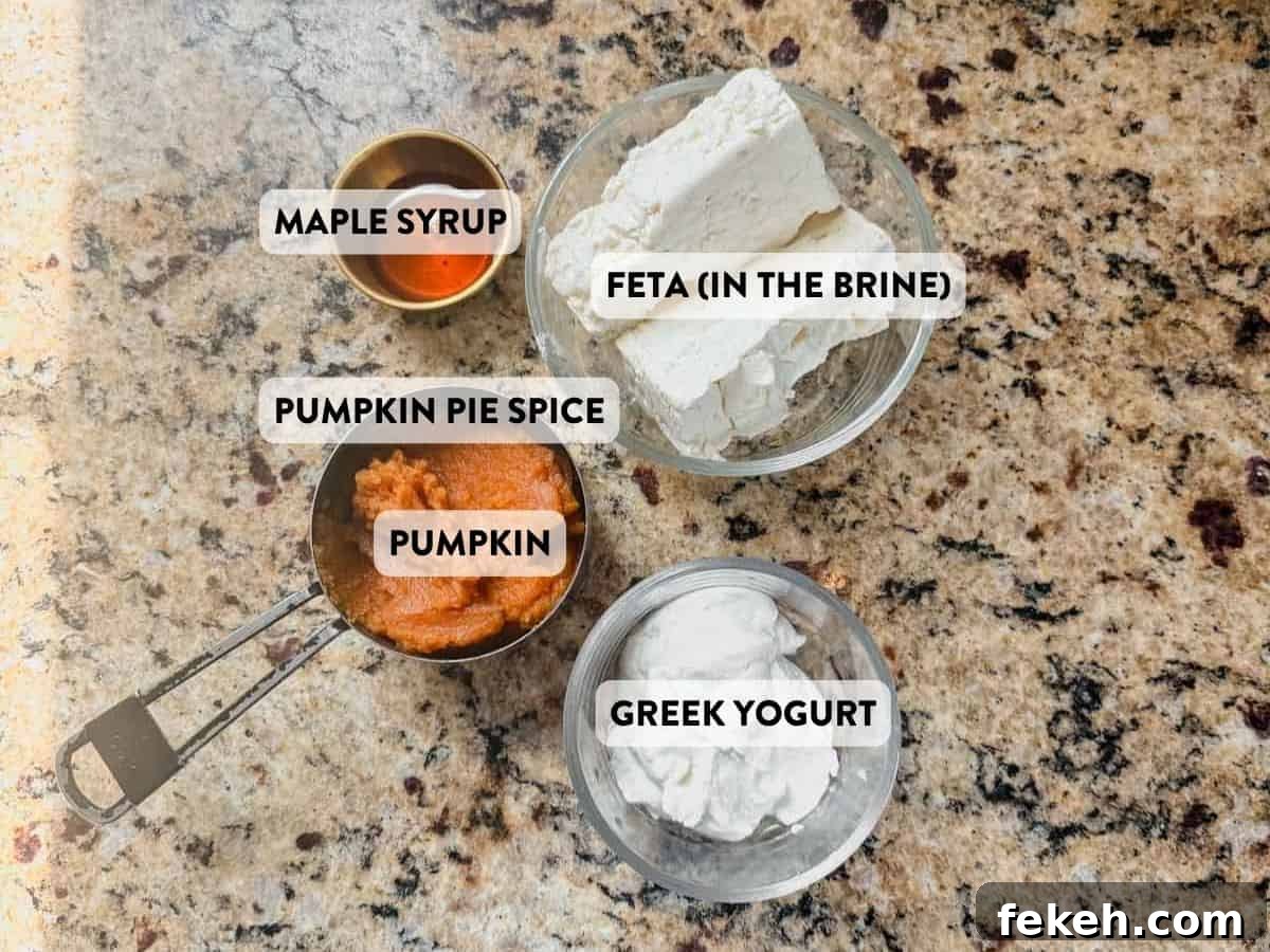 Creamy Pumpkin Whipped Feta Dip with Warm Spice and Herbs 4 feta, greek yogurt, pumpkin puree, maple syrup, and pumpkin pie spice on a counter.