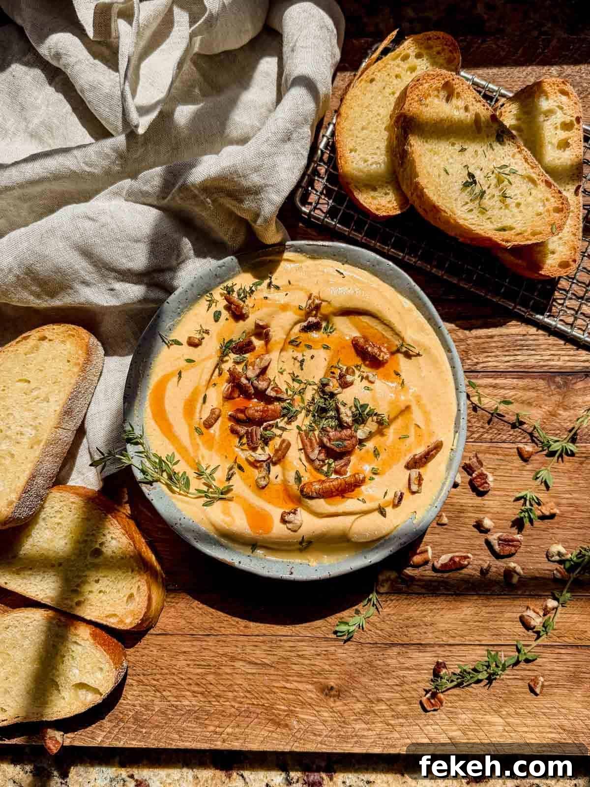 Creamy Pumpkin Whipped Feta Dip with Warm Spice and Herbs 6 pumpkin whipped feta in a serving bowl topped with honey, feta, and pecans.