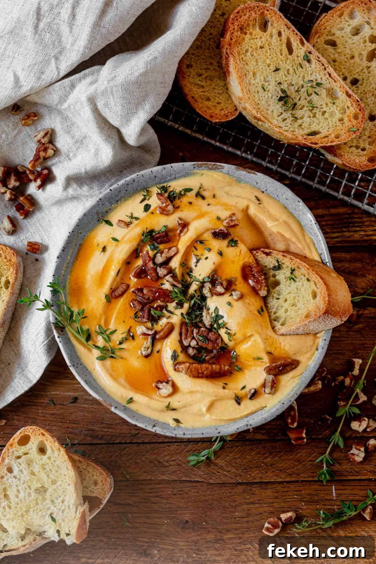 Creamy Pumpkin Whipped Feta Dip with Warm Spice and Herbs 7 a bowl of pumpkin whipped feta on a serving tray with crusty bread.