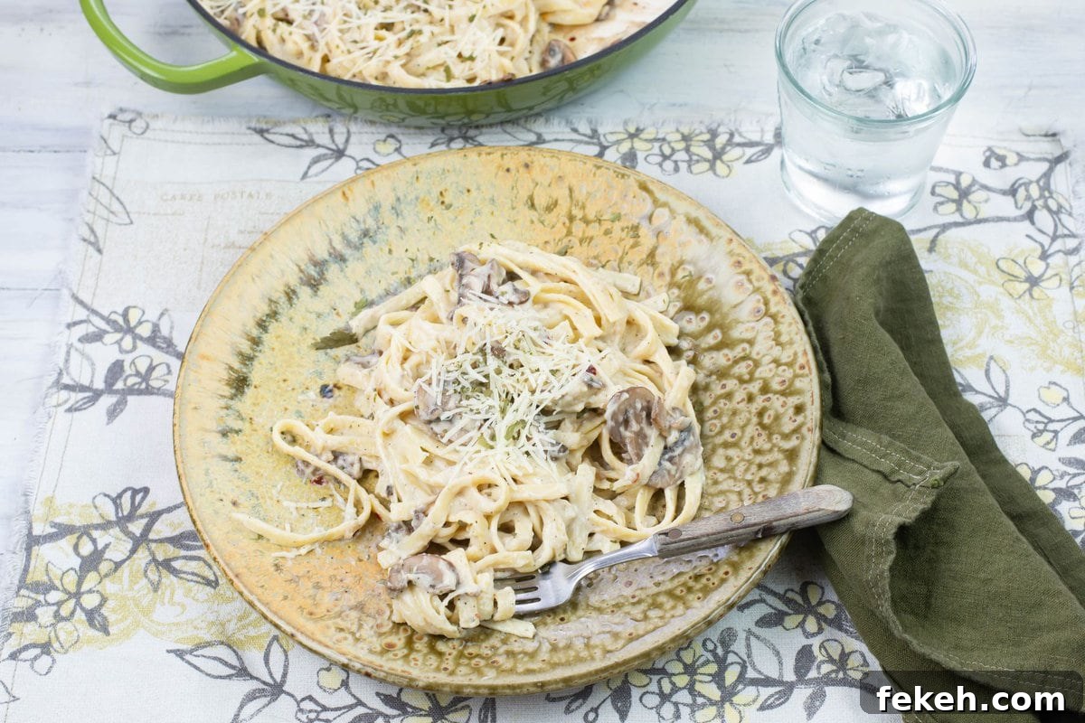 A serving of mushroom alfredo sauce with milk on a dinner plate with a skillet in the background.