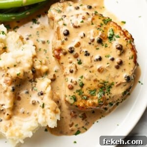 Creamy Peppercorn Sauce Pork Chops with Pan-Gravy 8 a plate with peppercorn pork chops, green beans, and mashed potatoes