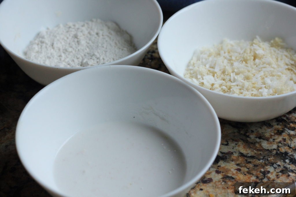 Crispy Air-Fried Coconut Shrimp Recipe with Tangy Dipping Sauce 3 Three bowls used to make coconut shrimp: flour, coconut milk, and panko with coconut flakes.