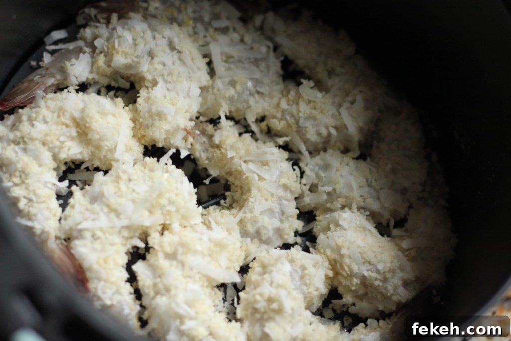 Crispy Air-Fried Coconut Shrimp Recipe with Tangy Dipping Sauce 4 Coconut shrimp arranged in the air fryer pan.
