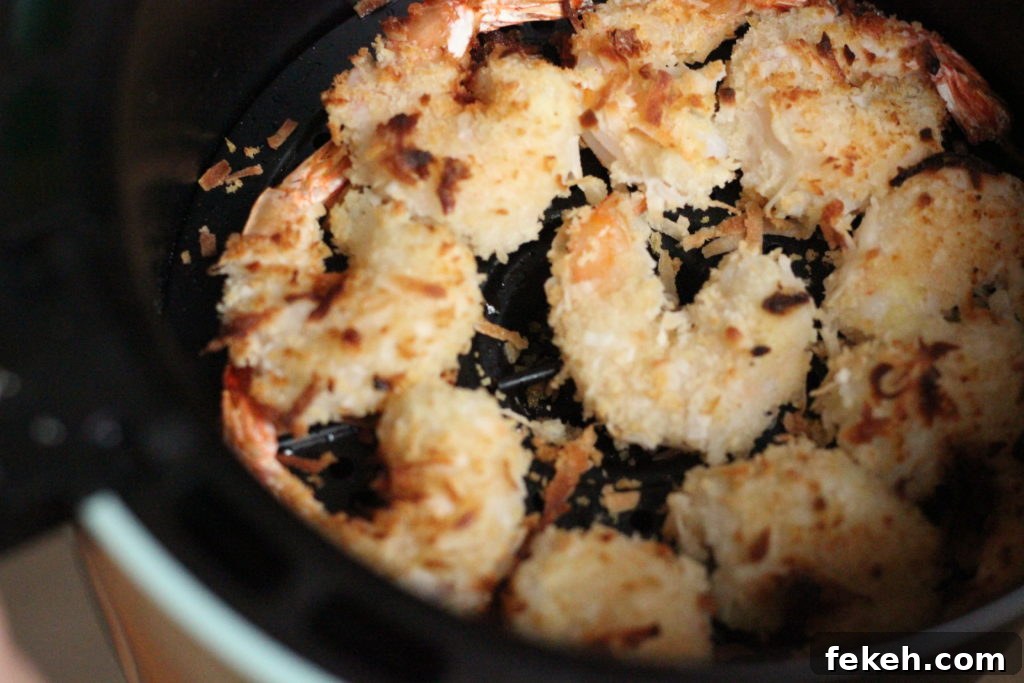 Crispy Air-Fried Coconut Shrimp Recipe with Tangy Dipping Sauce 5 Toasted coconut shrimp in an air fryer pan.