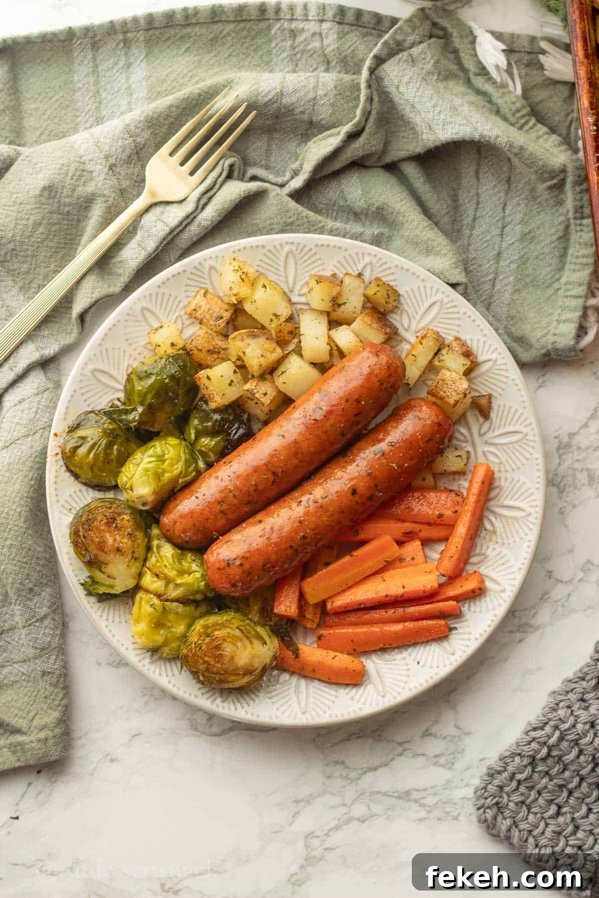 Sheet Pan Chicken Sausage with Roasted Veggies and Potatoes 2 Cooked chicken sausage with veggies on white plate.