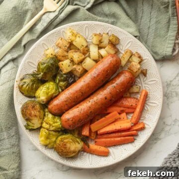Sheet Pan Chicken Sausage with Roasted Veggies and Potatoes 14 Cooked chicken sausage with veggies on white plate.