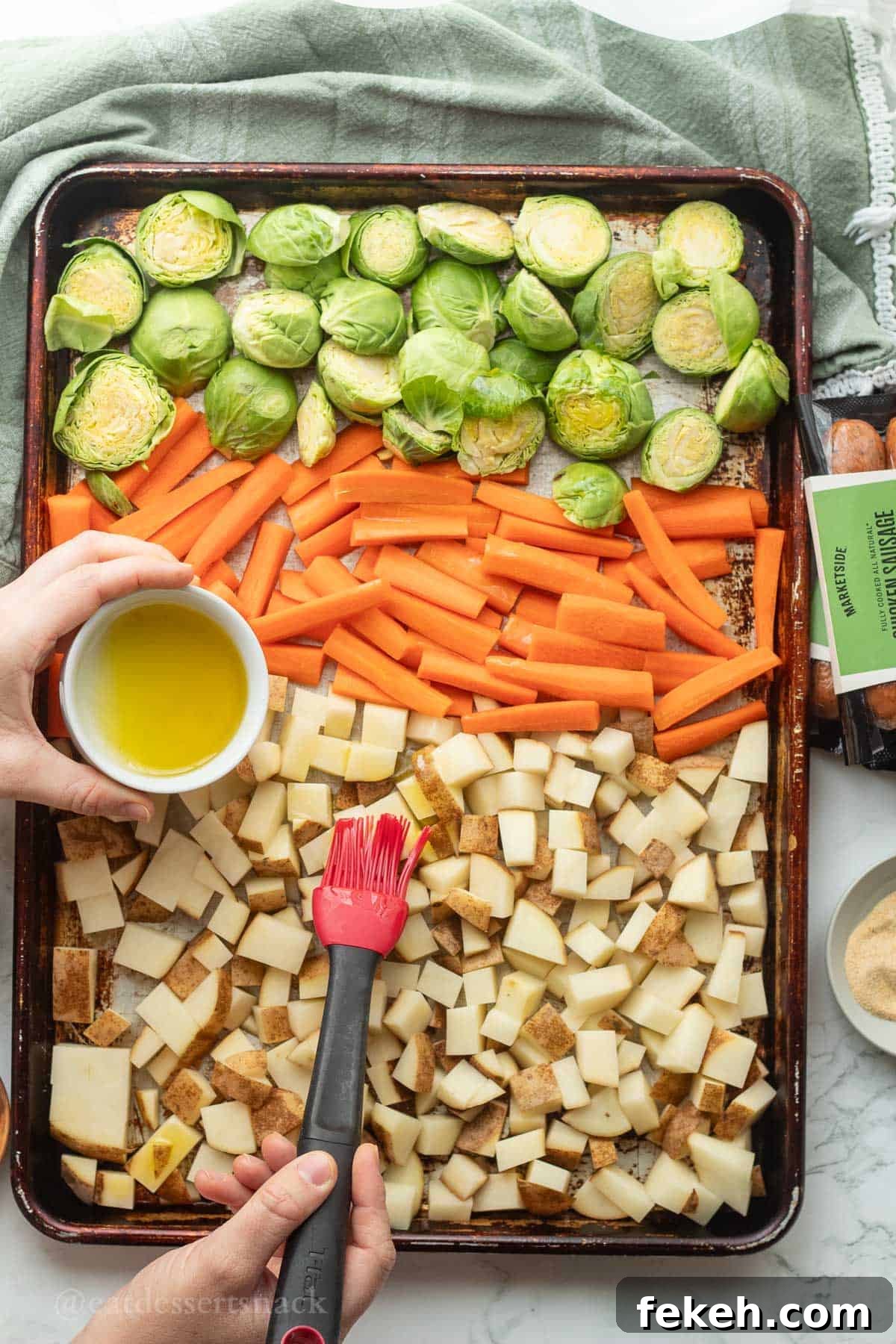 Sheet Pan Chicken Sausage with Roasted Veggies and Potatoes 6 Spreading olive oil over potatoes, carrots and brussels sprouts in metal pan.