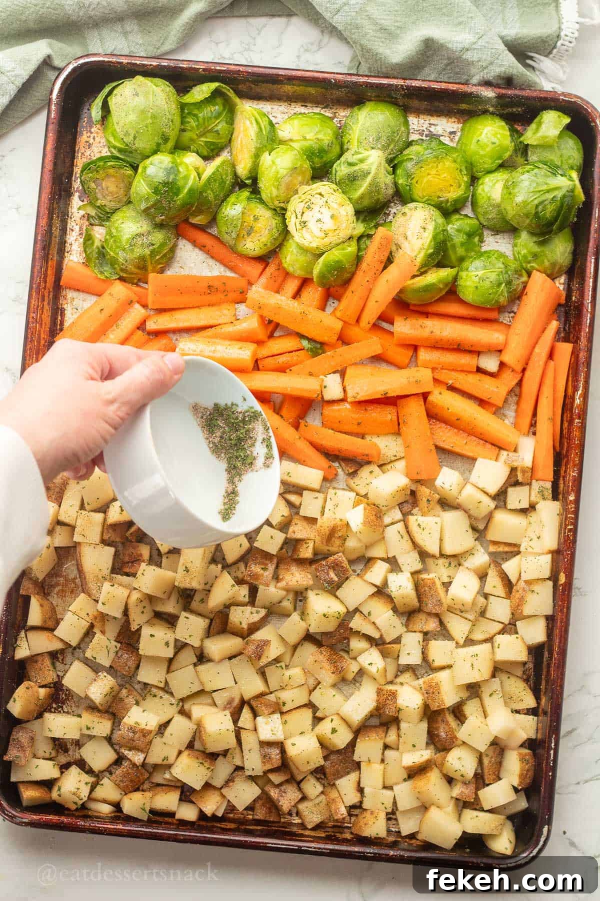 Sheet Pan Chicken Sausage with Roasted Veggies and Potatoes 7 Pouring seasoning over raw veggies in metal pan.