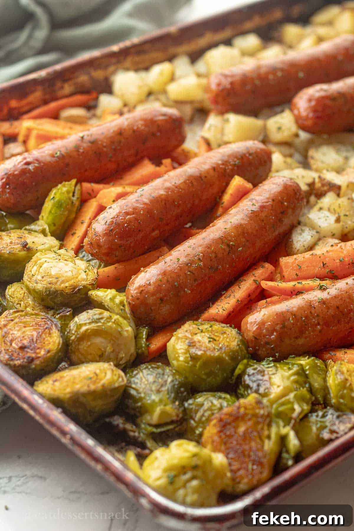 Sheet Pan Chicken Sausage with Roasted Veggies and Potatoes 9 Cooked chicken sausage with veggies on metal baking pan.