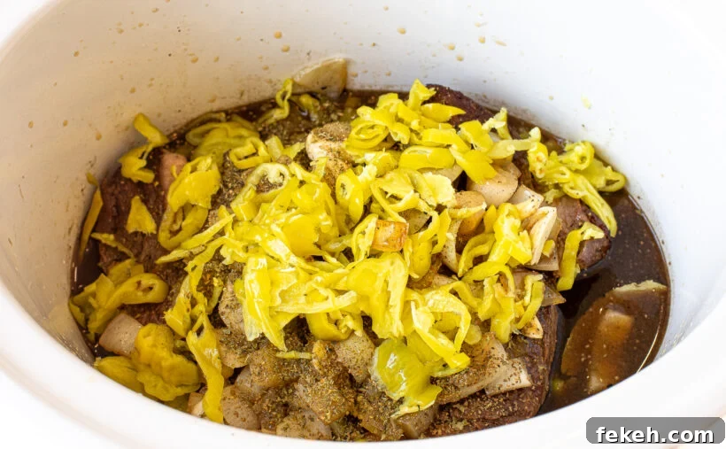Slow Cooker Italian Beef Sandwiches with Tender Shredded Beef 6 Chuck roast, pepperoncini, broth, onions and garlic in a slow cooker.