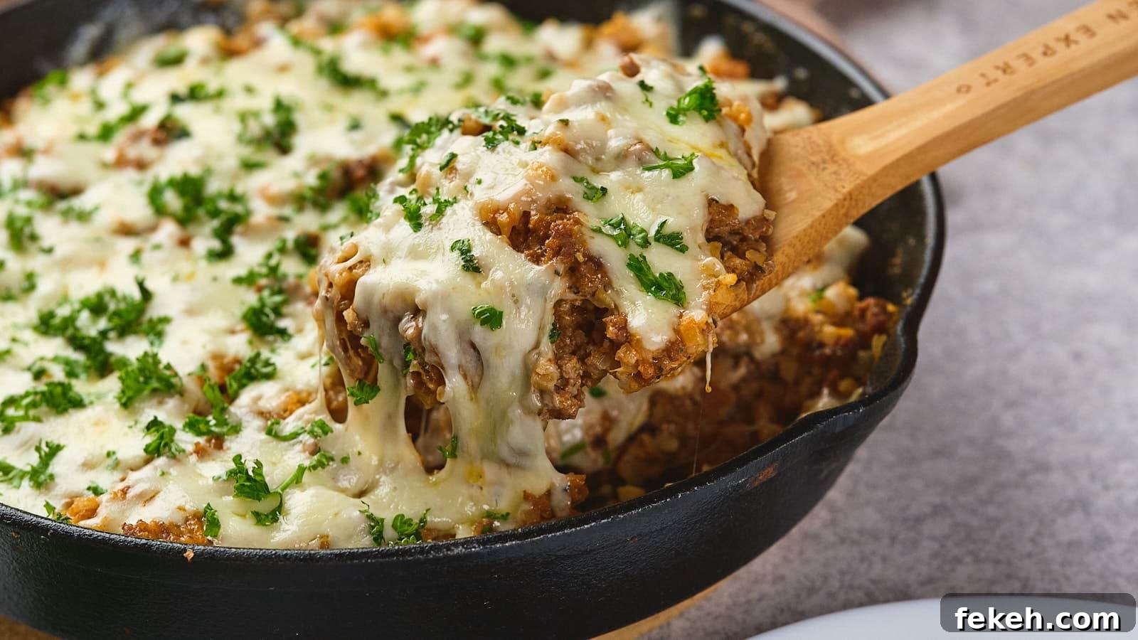 19 Kid-Approved Recipes Kids Beg For (Parents Love Them Too) 11 A wooden spoon lifting a serving of italian ground beef skillet garnished with parsley from a cast-iron skillet.