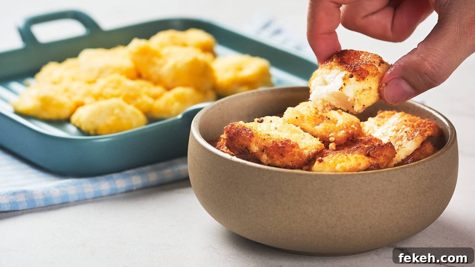 19 Kid-Approved Recipes Kids Beg For (Parents Love Them Too) 13 A hand picks up a piece of fried cheese curd from a bowl.