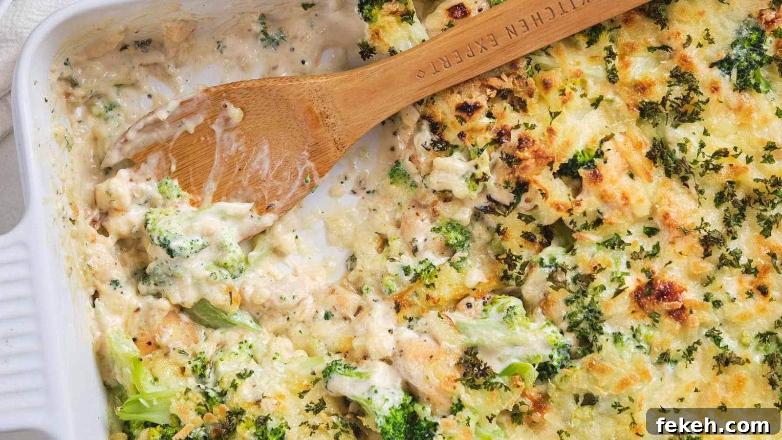 19 Kid-Approved Recipes Kids Beg For (Parents Love Them Too) 18 A wooden spoon scooping chicken broccoli alfredo casserole out of a serving dish.