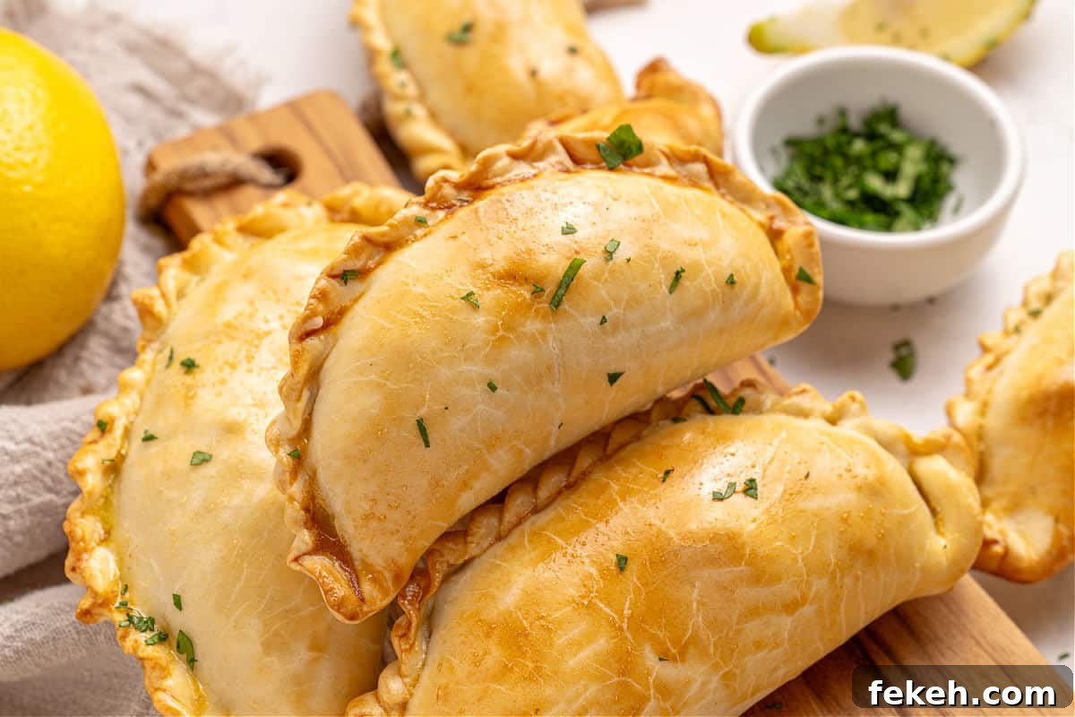 Knife-Cut Beef Empanadas: Crispy Handheld Meat Pastries 10 Pile of several baked empanadas. Bowl with chopped chives.