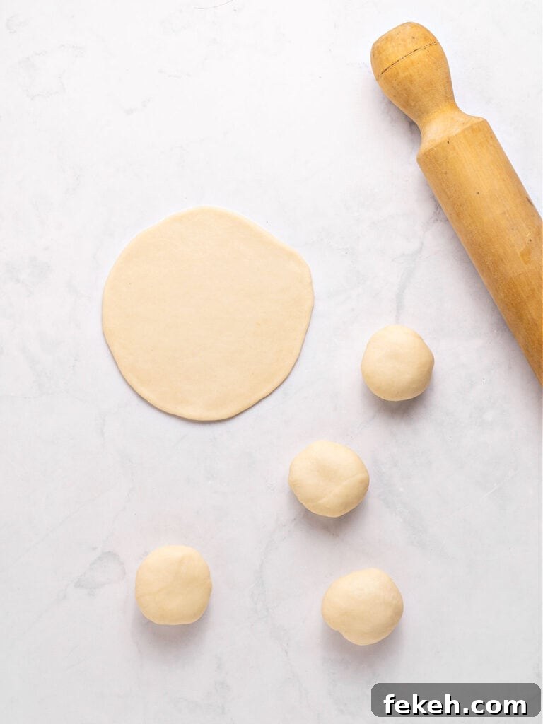 Knife-Cut Beef Empanadas: Crispy Handheld Meat Pastries 3 Rolling pin, empanada dough balls and circle. Light gray surface.
