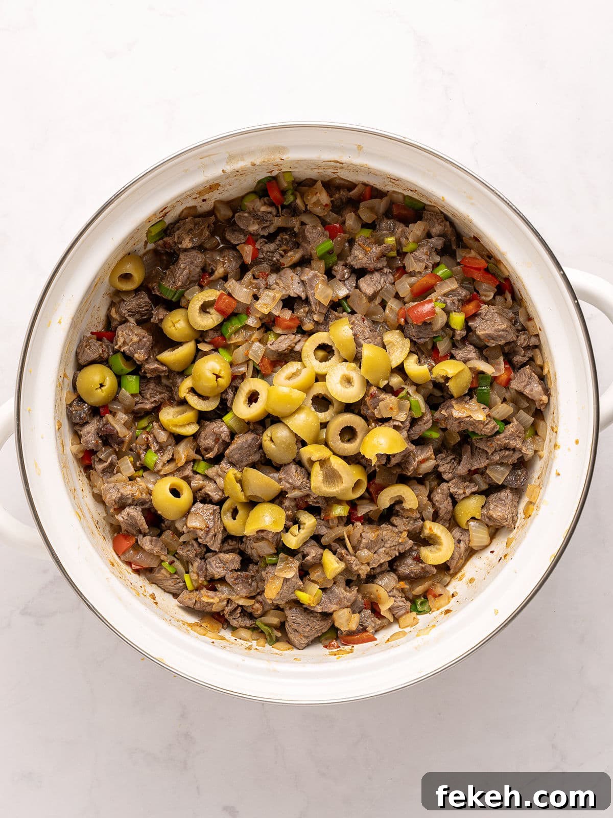 Knife-Cut Beef Empanadas: Crispy Handheld Meat Pastries 6 Cooked meat filling with olives for empanadas in a white saucepan. White background.