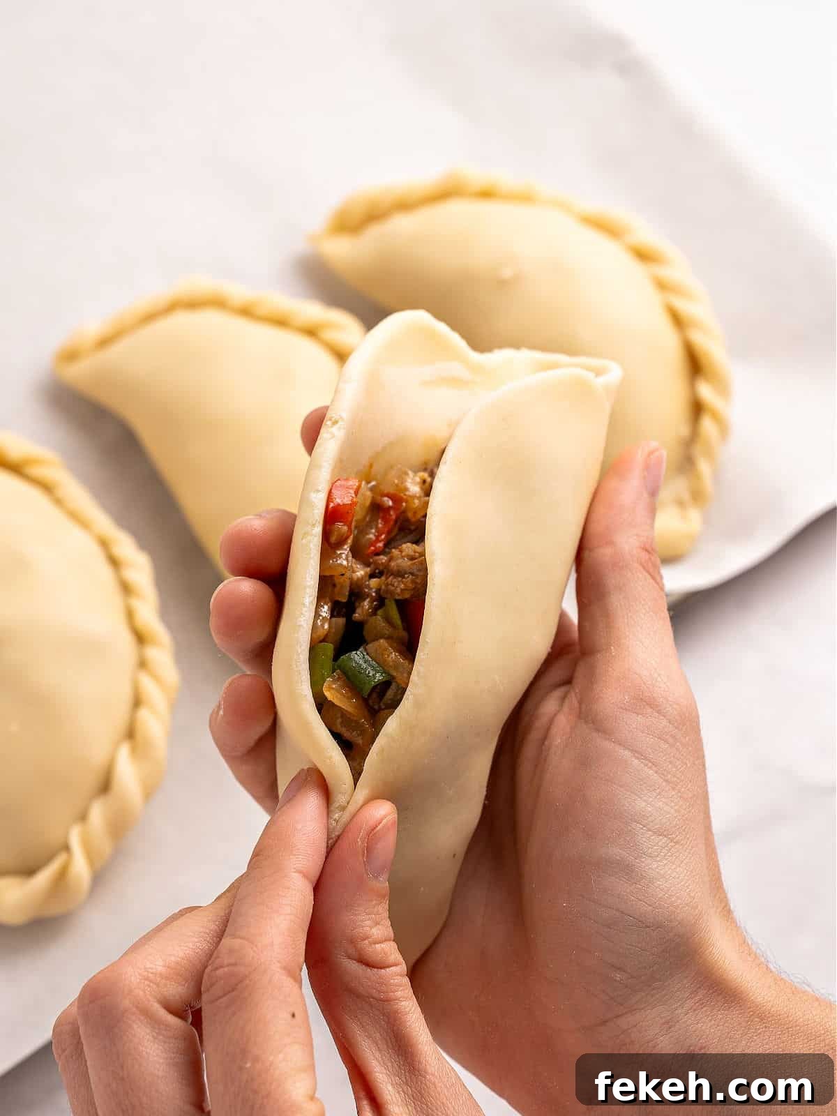 Knife-Cut Beef Empanadas: Crispy Handheld Meat Pastries 7 Closing an empanada dough in half with meat filling.