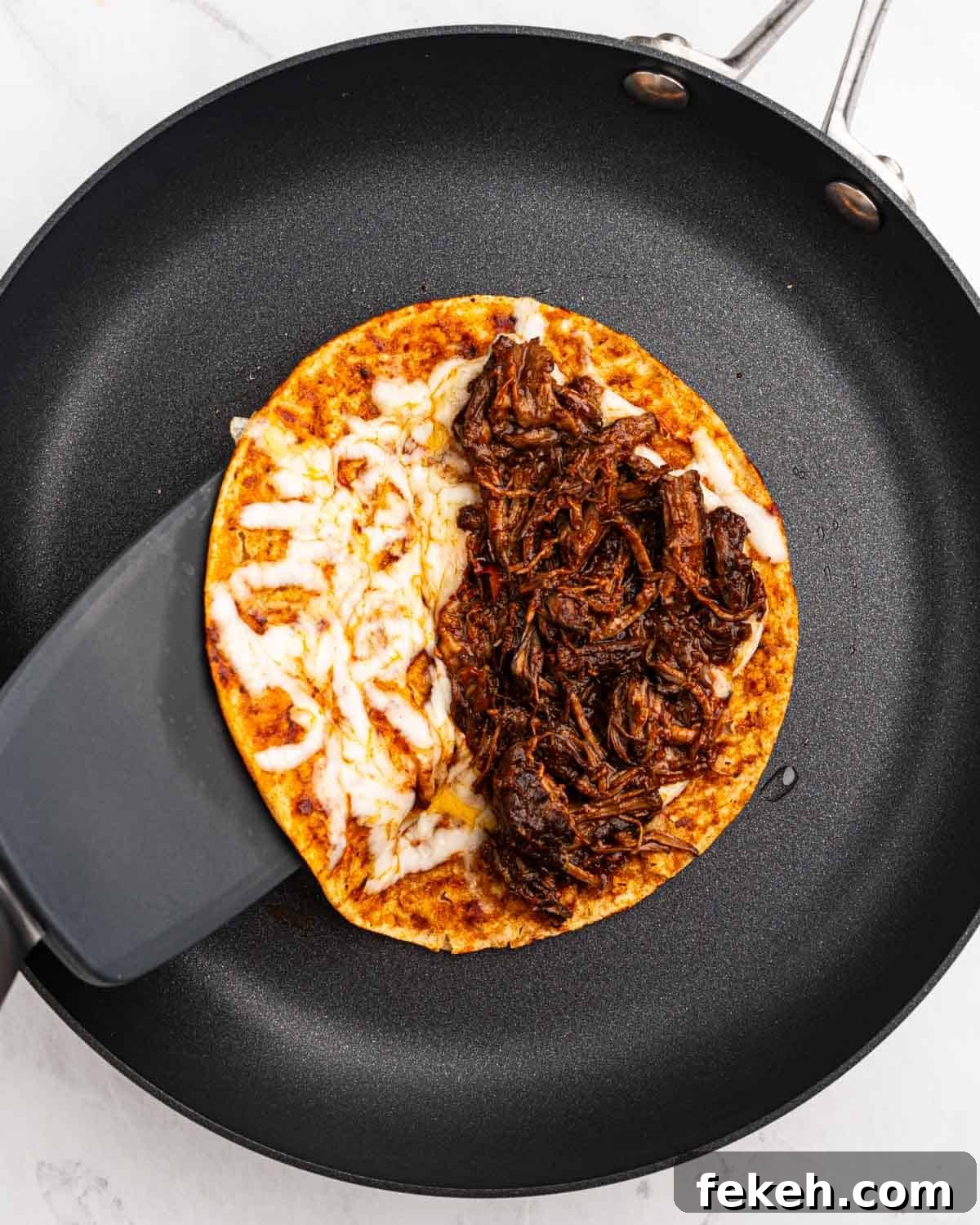 Authentic Quesabirria Tacos: How to Make Birria Tacos at Home 16 corn tortilla with melted cheese and birria meat on a pan.