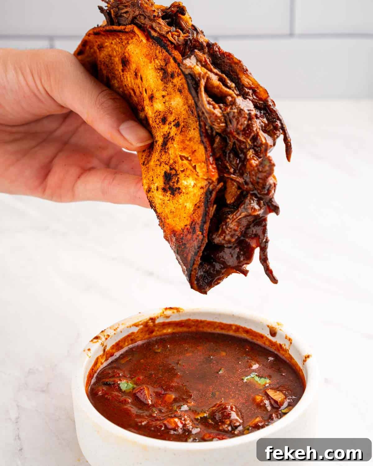 Authentic Quesabirria Tacos: How to Make Birria Tacos at Home 18 hand holding birria taco.