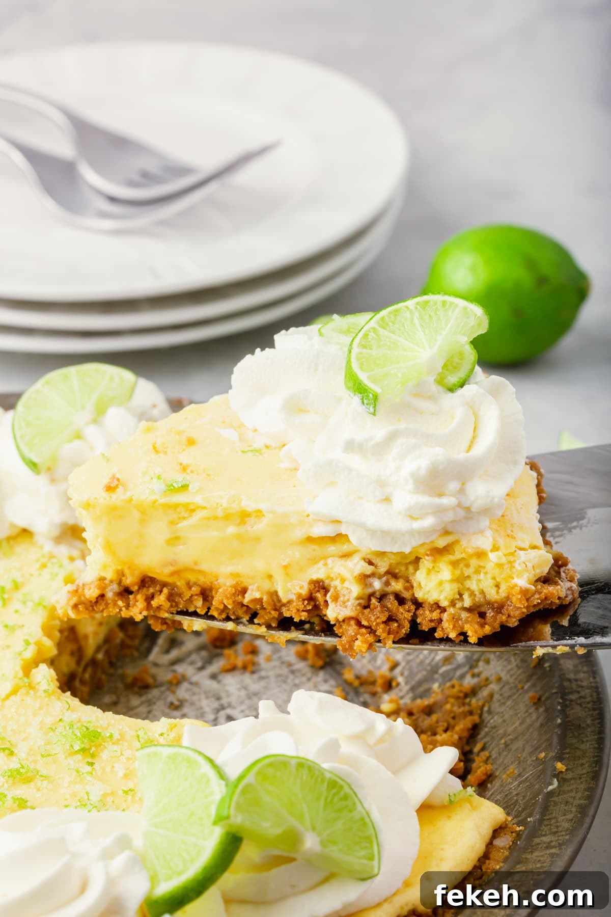 Gluten-Free Graham Cracker Pie Crust Recipe 5 A piece of key lime pie with graham cracker crust being lifted out of a pie tin with a spatula.