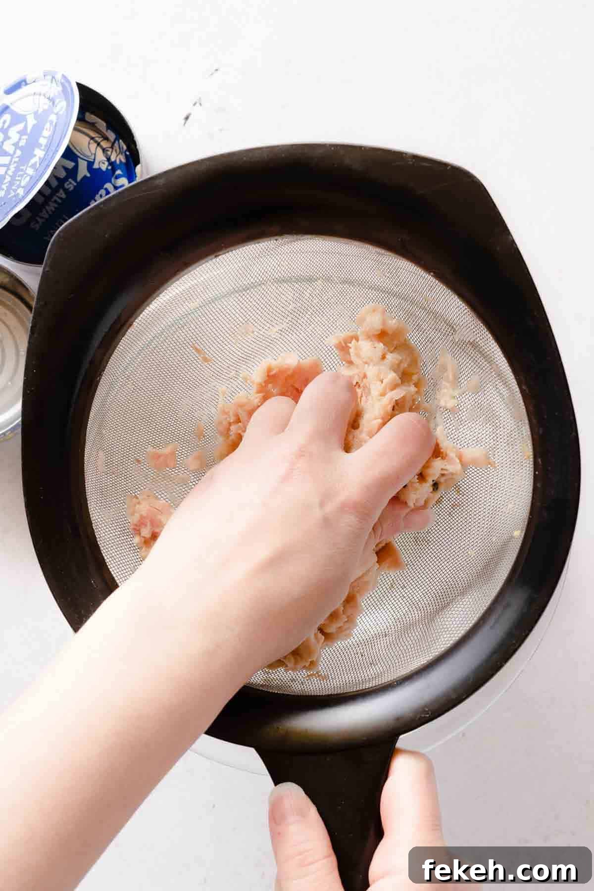 Greek Yogurt Tuna Salad Recipe Without Mayo — High-Protein Lunch 9 hand squeezing moisture from tuna over strainer