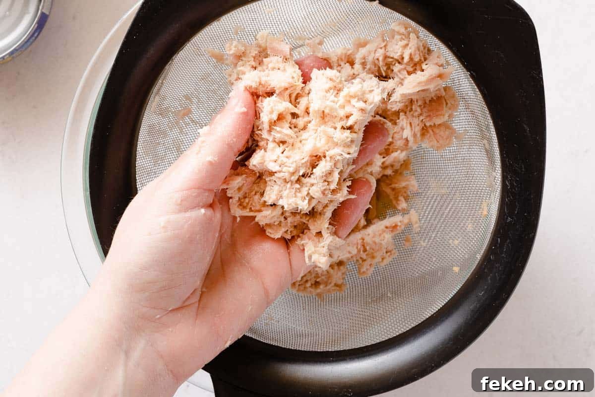 Greek Yogurt Tuna Salad Recipe Without Mayo — High-Protein Lunch 10 hand holding drained tuna over strainer