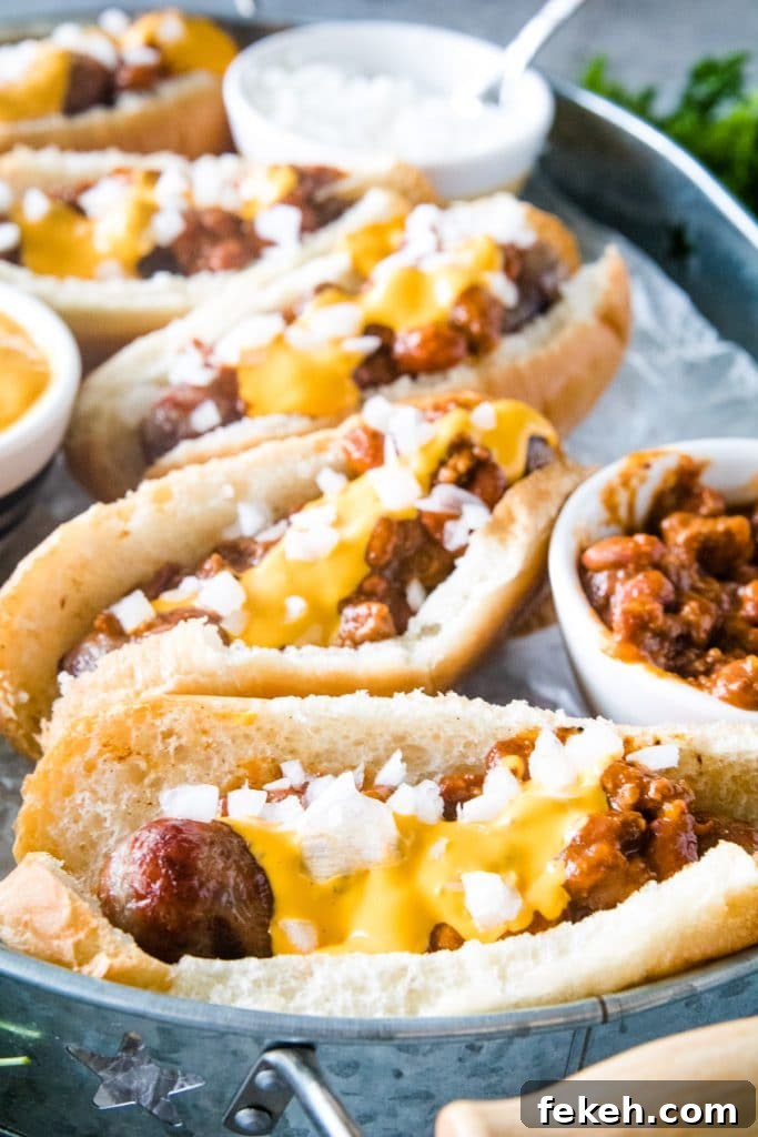 Spicy Chili Cheese Bratwurst Sandwiches for Game Day 2 Chili Cheese Brats topped and ready to serve. Sitting in a silver serving tray.