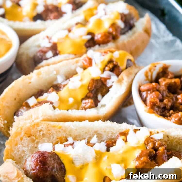 Spicy Chili Cheese Bratwurst Sandwiches for Game Day 7 Chili Cheese Brats topped and ready to serve. Sitting in a silver serving tray.