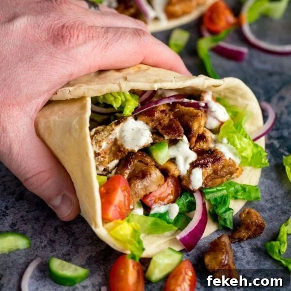 Grilled Chicken Souvlaki Recipe: Tender Mediterranean Skewers 12 Chicken Shawarma in a pita being held by a hand