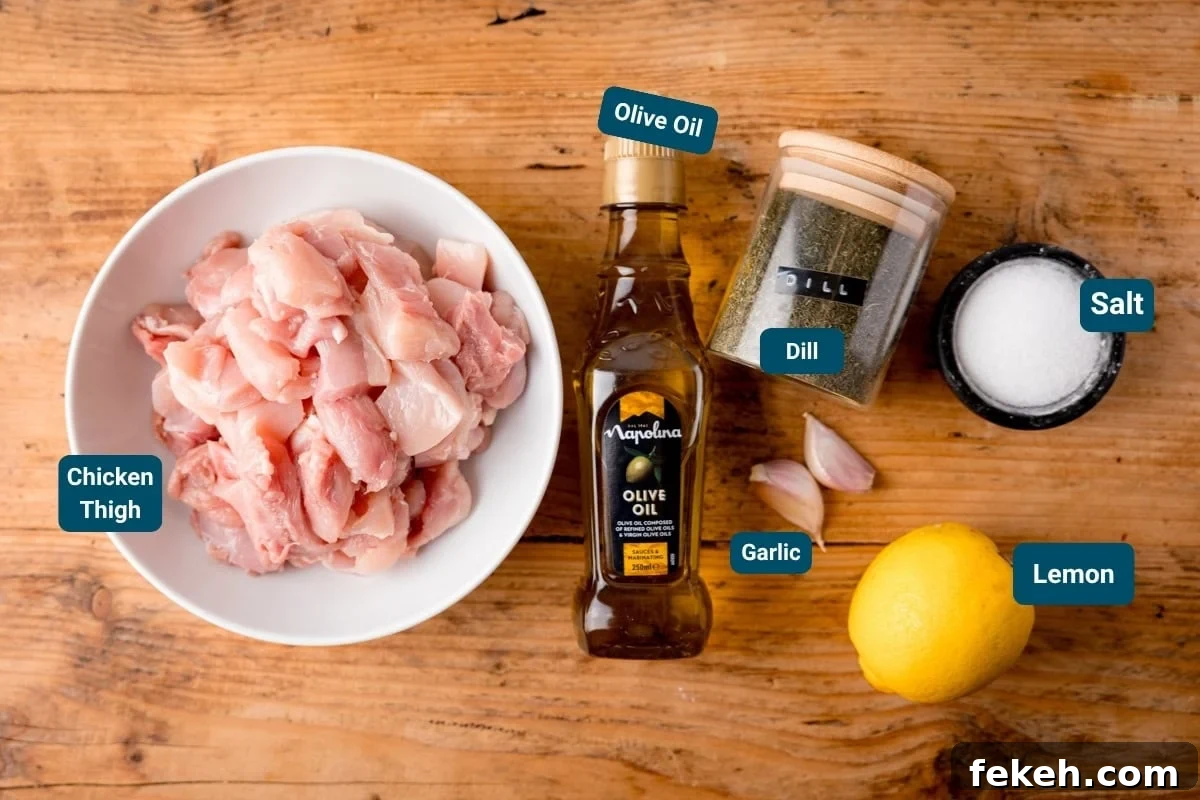 Grilled Chicken Souvlaki Recipe: Tender Mediterranean Skewers 4 Labelled ingredients for chicken souvlaki on a wooden table, including: chicken thigh pieces, olive oil, dill, garlic cloves, salt, and a whole lemon.