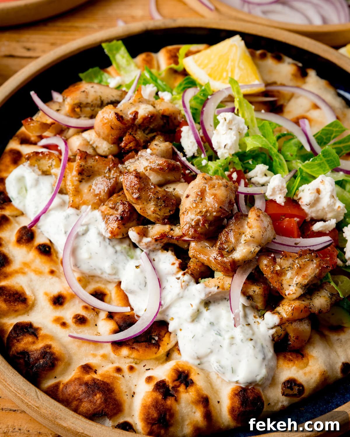 Grilled Chicken Souvlaki Recipe: Tender Mediterranean Skewers 6 Chicken Souvlaki with tzatziki, lettuce, tomato, red onion and feta on toasted flatbread with a lemon wedge.
