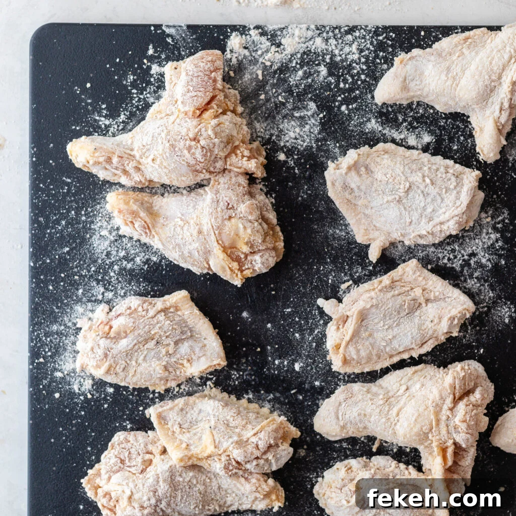 Crispy Southern Fried Chicken Wings Recipe for Perfect Crunch 7 chicken wings coated in seasoned flour sitting on a black cutting board