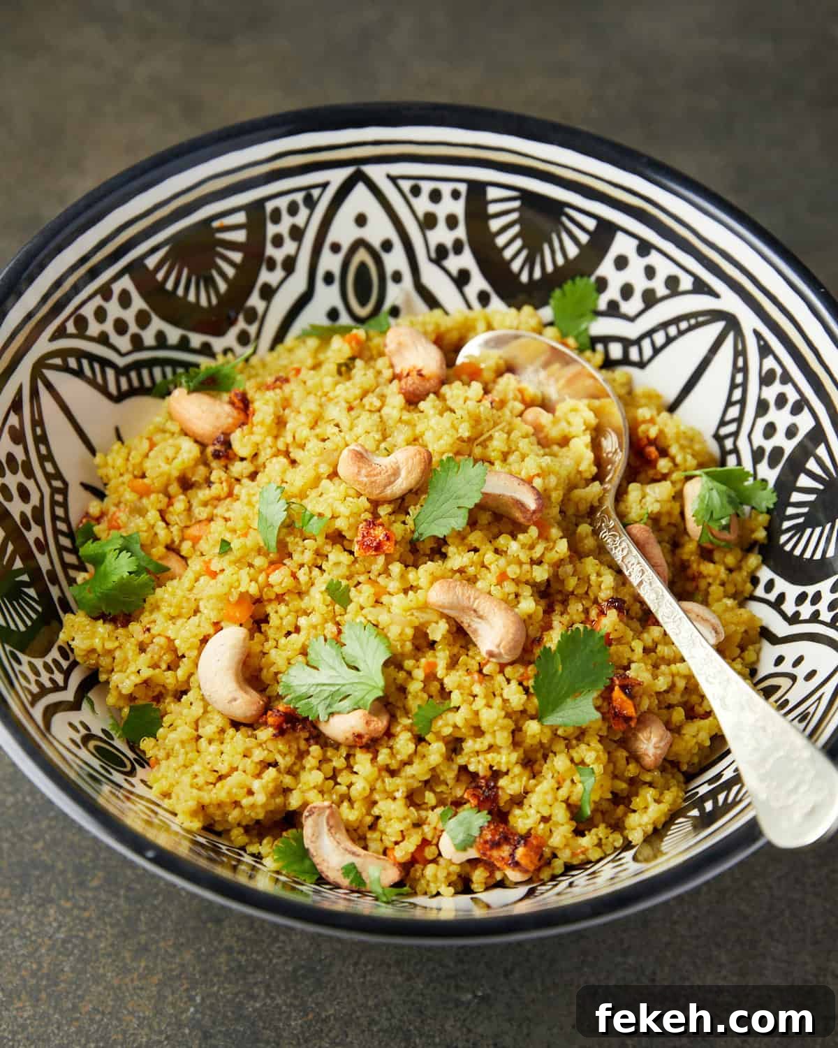 How to Cook Millet Perfectly on Stovetop or Instant Pot 8 Photo of millet pilaf in a black and white patterned bowl on a green background.