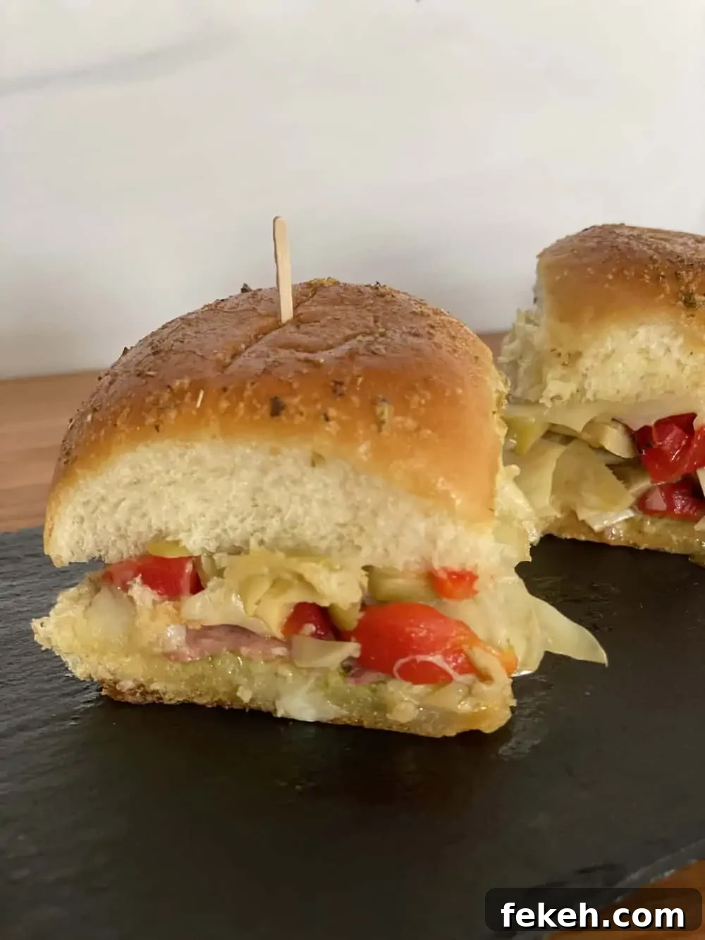Antipasto Sliders on King's Hawaiian Rolls: Italian Sandwich Recipe 3 Antipasto Sliders on a black serving tray.