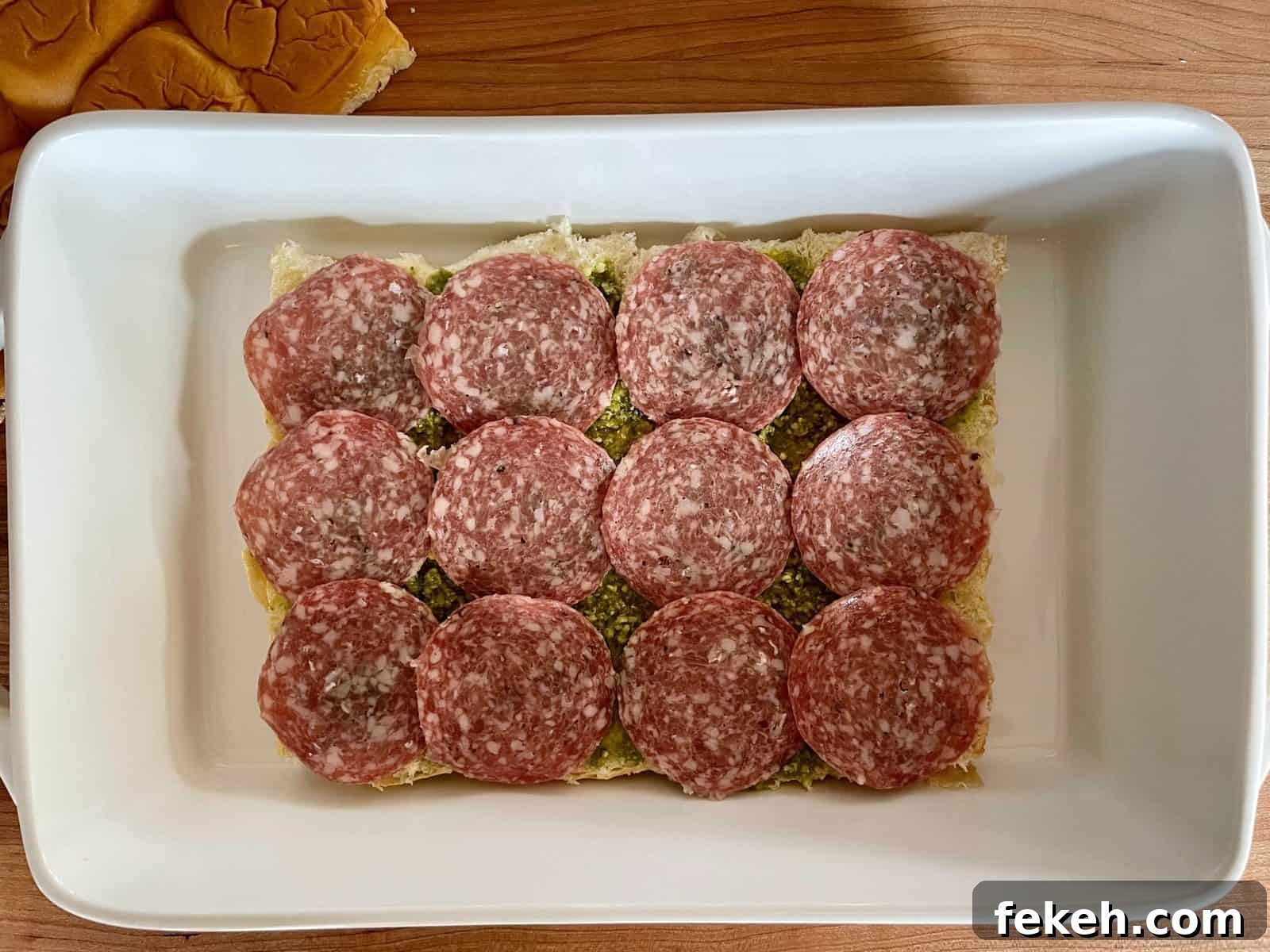 Antipasto Sliders on King's Hawaiian Rolls: Italian Sandwich Recipe 6 Overhead photo of salami layered over top of the pesto on the bottom half of the rolls.