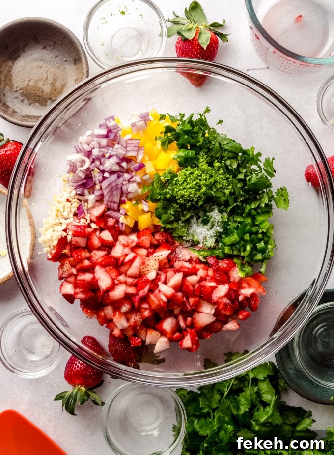Fresh Strawberry Salsa Recipe: Zesty Fruit Salsa for Chips & Tacos 8 Strawberries, red onion, yellow bell pepper, lime, jalapeño, garlic, and cilantro in a bowl to make strawberry salsa.