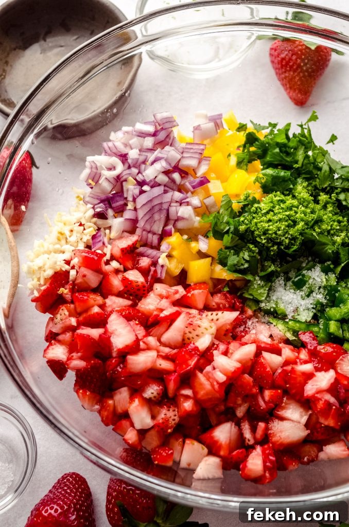 Fresh Strawberry Salsa Recipe: Zesty Fruit Salsa for Chips & Tacos 9 Strawberries, red onion, yellow bell pepper, lime, jalapeño, garlic, and cilantro in a bowl to make strawberry salsa.