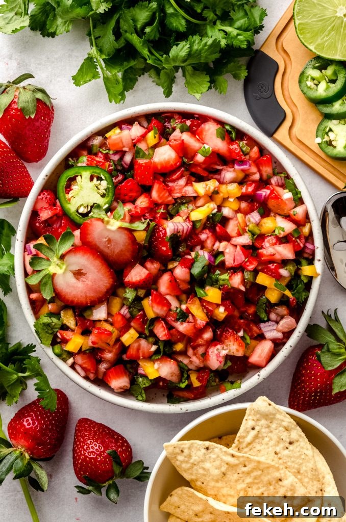 Fresh Strawberry Salsa Recipe: Zesty Fruit Salsa for Chips & Tacos 10 An aerial photo of a bowl of fresh strawberry salsa with fresh strawberries and chips around it.