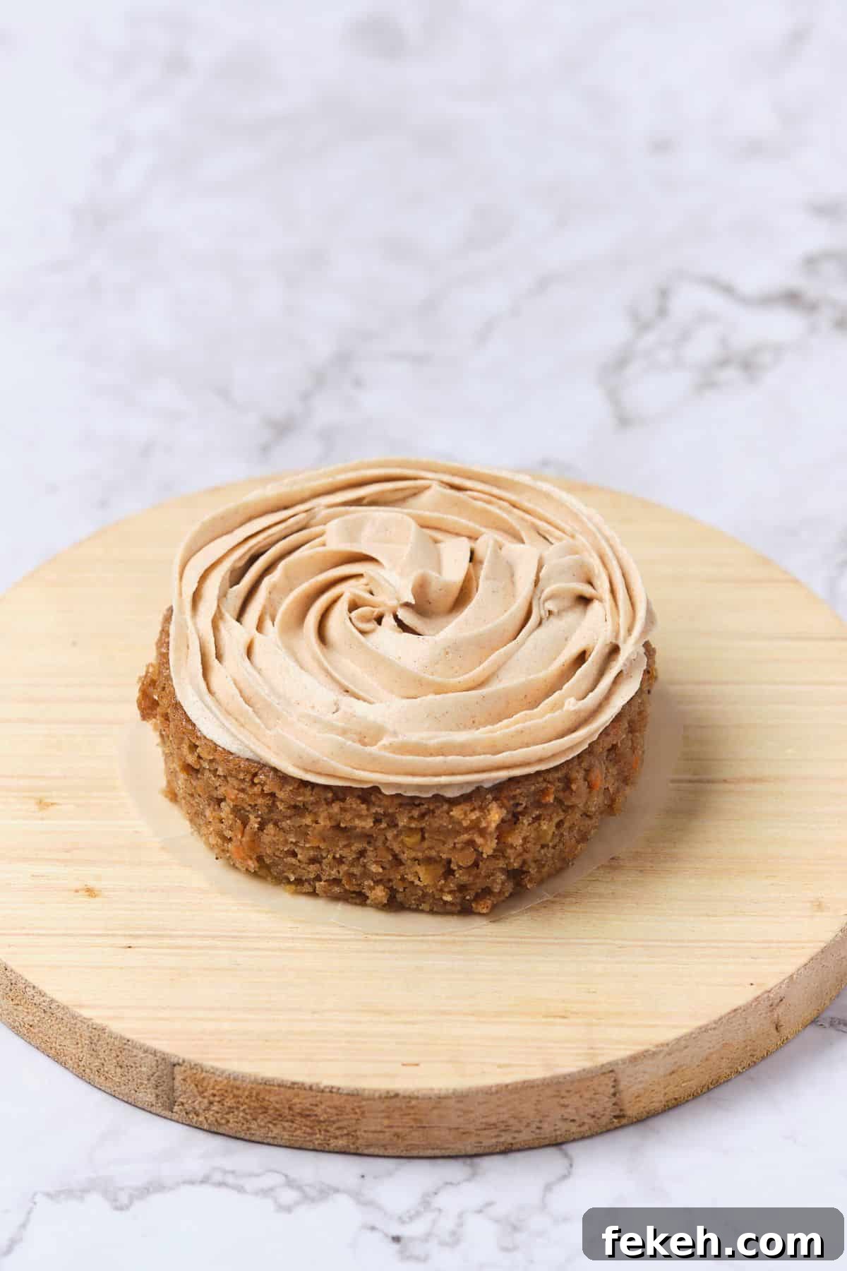 Moist Mini Carrot Cake Bites: Perfect Party Cupcakes 10 A small carrot cake being frosted with cinnamon cream cheese buttercream.