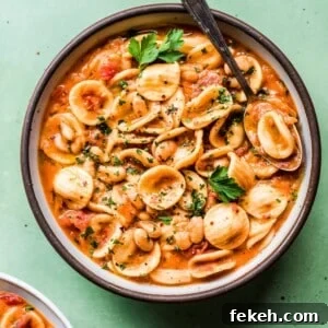 Italian White Bean and Pasta Stew with Garlic & Herbs (Vegan) 6 italian pasta and white bean stew in a ceramic bowl on a green surface.