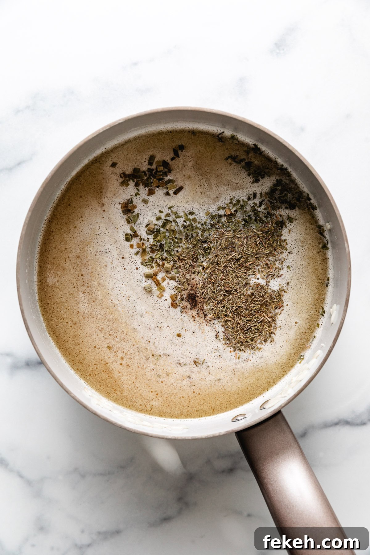 Broth, herbs and rice in a pan.