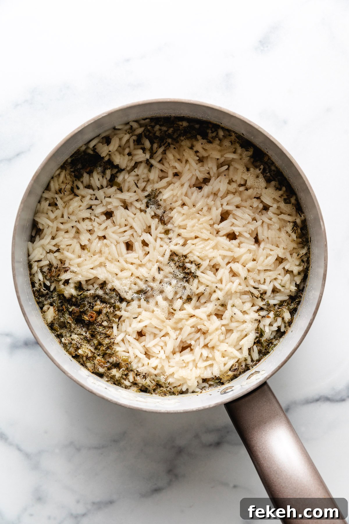Herbs and rice cooking in a pan.