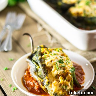 Baked Chorizo and Butternut Squash Chile Rellenos Recipe 10 A single chorizo-butternut squash chile relleno on a plate with ranchero sauce. In the background is the pan, plate, forks and cilantro.