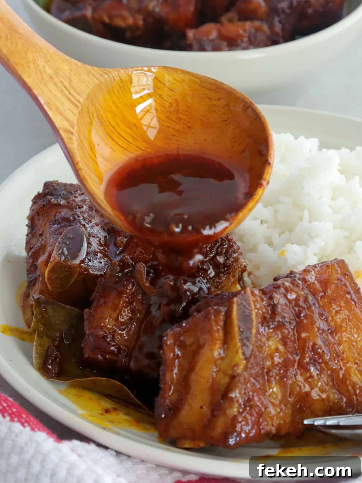 Pork Ribs Adobo with Atsuete Oil Infusion 5 pouring sauce over adobong pula with steamed rice on a white plate
