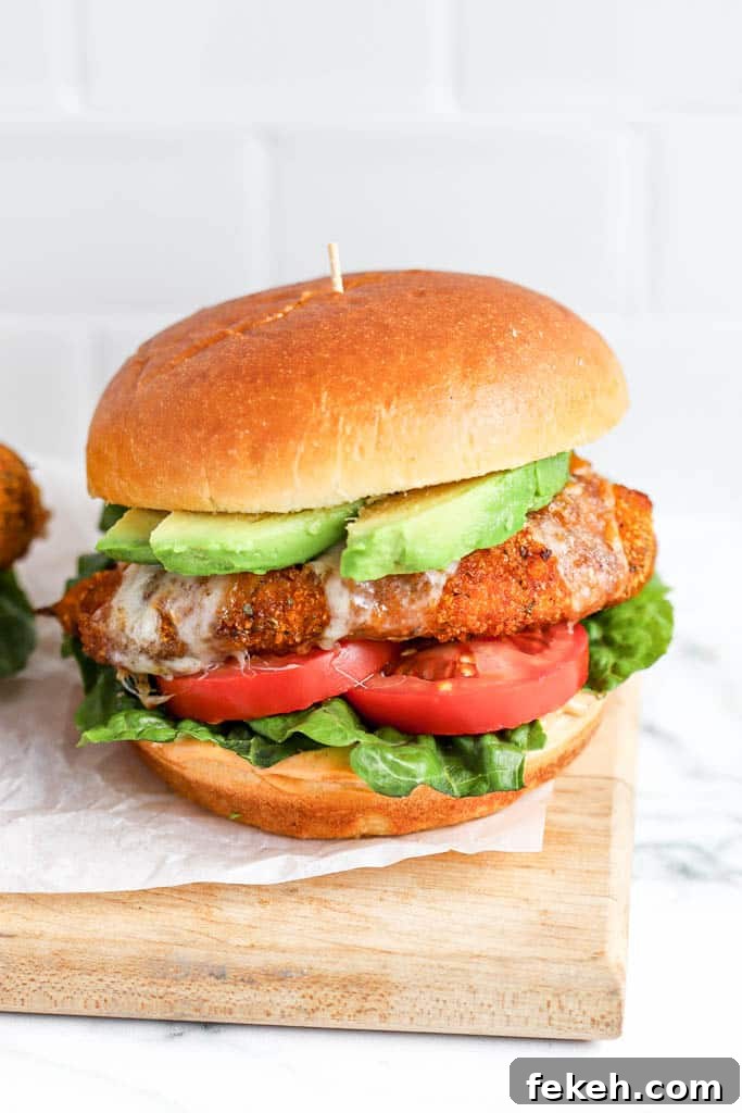Crispy Air Fryer Chicken Burger Recipe for Juicy Patties 3 close up of crispy air fryer chicken burger with melted cheese, lettuce, avocado, and tomato on toasted bun