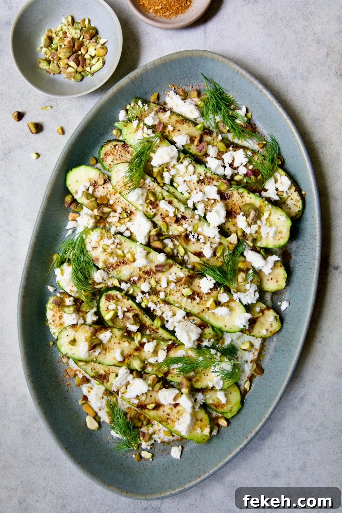 Mediterranean Grilled Zucchini with Dill Yogurt & Feta 11 Mediterranean Grilled Zucchini with Dill Yogurt and Feta on blue platter garnished with pistachios and fresh dill sprigs.