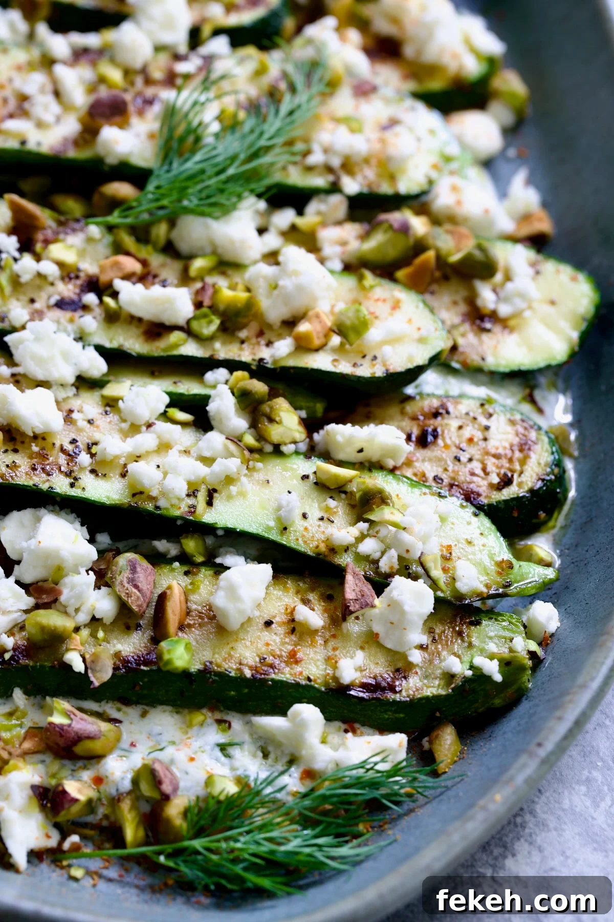 Mediterranean Grilled Zucchini with Dill Yogurt & Feta 13 Mediterranean Grilled Zucchini with Dill Yogurt and Feta on blue platter garnished with pistachios and fresh dill sprigs.