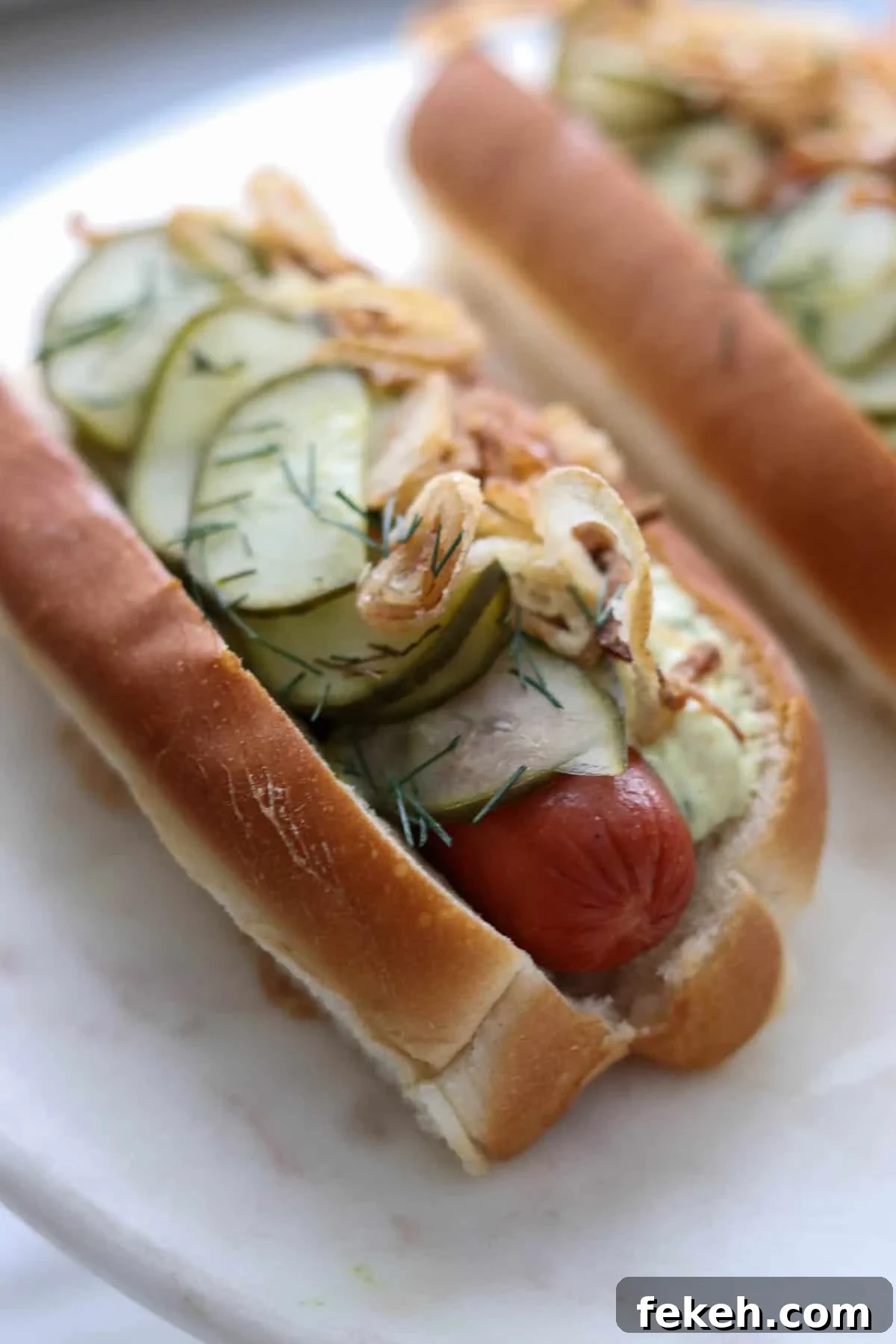 Danish Hot Dogs (Rød Pølse) in a bun covered with pickles and onions.